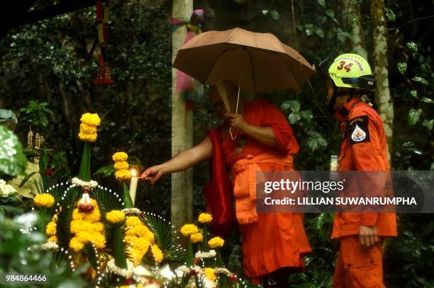 Buddhist monk prays next to a rescuer at a small temple near the entrance of the Tham Luang cave at the Khun Nam Nang Non Forest Park in Chiang Rai...