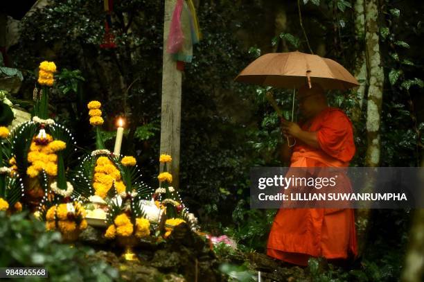 Buddhist monk prays at a small temple near the entrance of the Tham Luang cave at the Khun Nam Nang Non Forest Park in Chiang Rai on June 27, 2018...