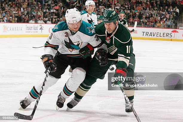 Owen Nolan of the Minnesota Wild and Douglas Murray of the San Jose Sharks skate to the puck during the game at the Xcel Energy Center on April 2,...