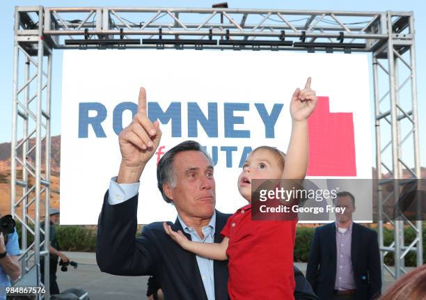 Mitt Romney and his grandson Dane Romney point to a plane in the sky after his victory rally on June 26, 2018 in Orem, Utah. Romney was declared the...
