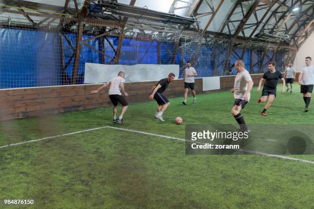 mid aged men playing amateur soccer in indoor arena - futsal stock pictures, royalty-free photos & images