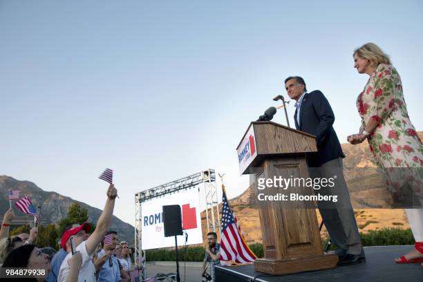 Attendees wave flags as Mitt Romney, Republican U.S Senate candidate, second right, speaks on stage while wife Ann Romney, right, looks on during an...