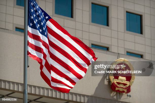 The American flag flies near the national emblem of China outside of the Bayi Building during a welcome ceremony for US Defence Secretary Jim Mattis...