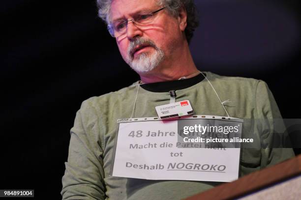 Member Harald Braun carrying a sign with the inscription "48 years of membership - Do not kill the party - Thus No Grand Coalition" during the SPD's...