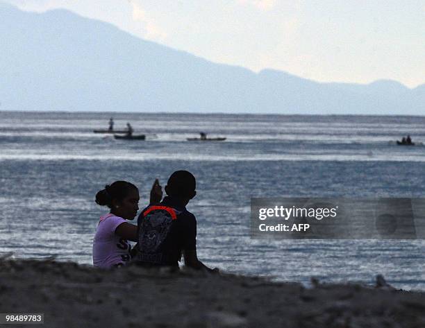 To go with AFP story by Matt Crook: TIMOR-WOMEN-EDUCATION-YOUTH-FAMILY A young couple sit together on the beach in Dili on March 28, 2010. The...