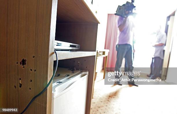 Thai media workers stand next to the cabinet with bullet holes as Thai security forces attempt to arrest Red Shirt leaders and what they are...