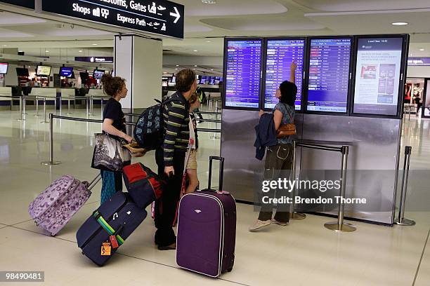 Passengers check flights at the departure board as flights are delayed and cancelled following the eruption of iceland's Eyjafjallajokull volcano, at...
