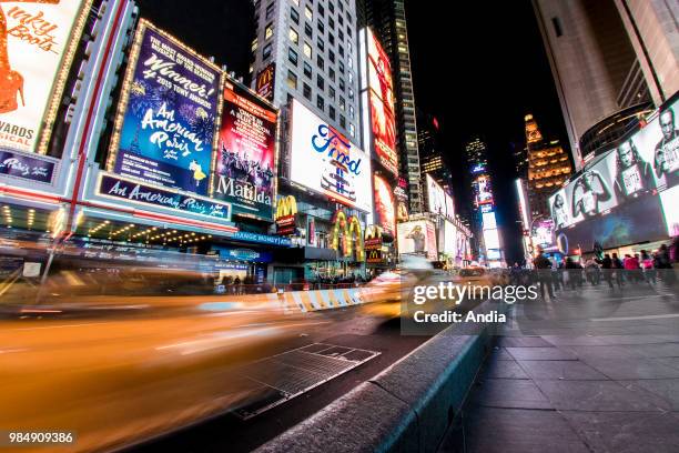 Time Square at night, atmosphere, traffic and illuminated advertising on building facades.