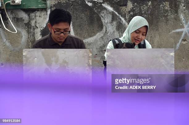 An Indonesian couple votes during regional elections in Tangerang, Banten on June 27, 2018. - Tens of millions of Indonesians will vote on June 27 in...