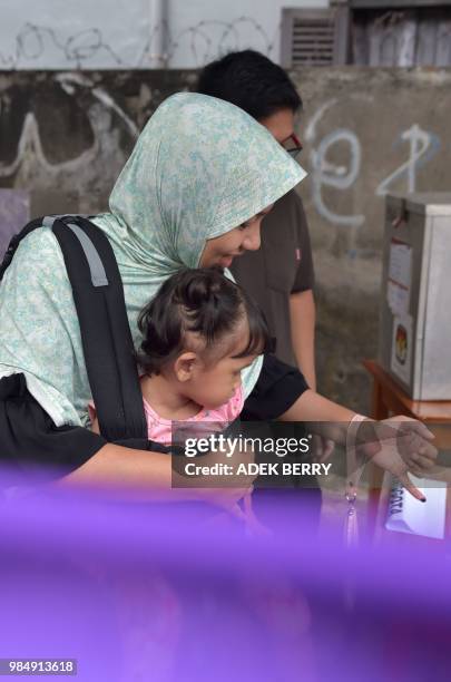 An Indonesian woman gets her finger inked after casting her ballot during regional elections in Tangerang, Banten on June 27, 2018. - Tens of...