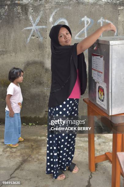 An Indonesian woman casts her ballot during regional elections in Tangerang, Banten on June 27, 2018. - Tens of millions of Indonesians will vote on...