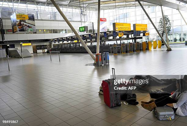 Passengers rest on the floor of the departure lounge at Amsterdam Schiphol airport on April 16 following the closure of Dutch airspace. Dutch...
