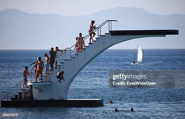 Swimmers are jumping from a diving platform into the aegean sea on July 16, 2009 in Rhodes, Greece. Rhodes is the largest of the Greek Dodecanes...
