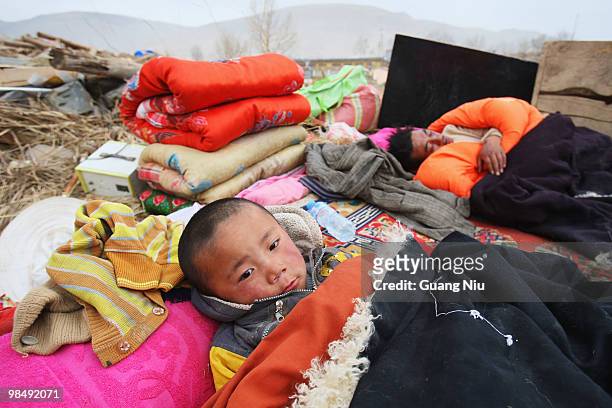 Tibetan child and his father sleep outside under blankets following a strong earthquake, on April 16 in Jiegu, near Golmud, China. It is currently...