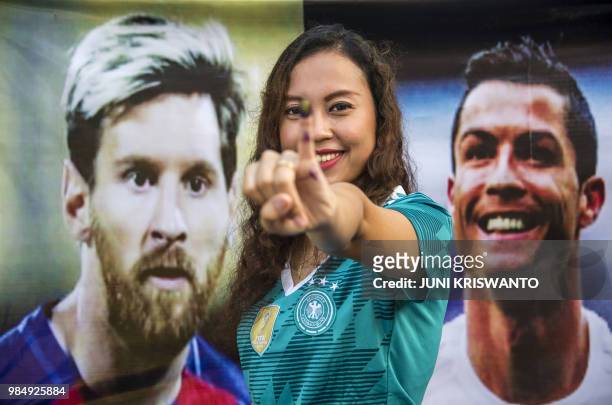 An Indonesian voter poses with her inked finger past portraits of football stars Lionel Messi and Cristiano Ronaldo at a football-themed polling...