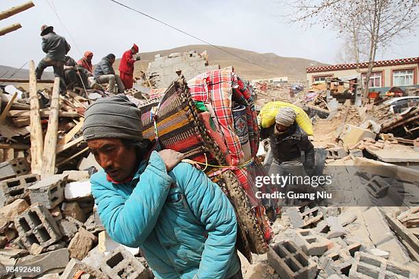 Locals gather their belongings and move them out through the rubble following a strong earthquake on April 16, 2010 in Jiegu, near Golmud, China. It...