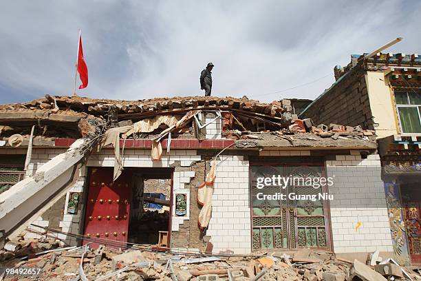 Local stands on the roof of a partly collapsed building and observes the surrounding damage from an earthquake on April 16, 2010 in Golmud, China. It...