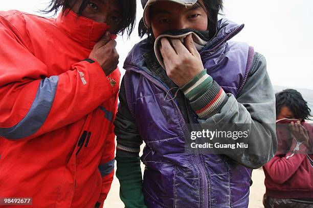 Young locals cover their faces as soldiers and rescue workers continue efforts to save people from collapsed buildings on April 16 in Golmud, China....