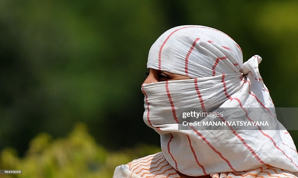 An Indian woman wraps her face with a cl