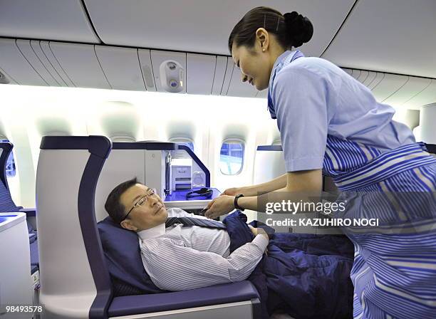 Employees of Japan's All Nippon Airways introduce the Business class seats in the company's new passenger plane Boeing 777-300ER during a press...