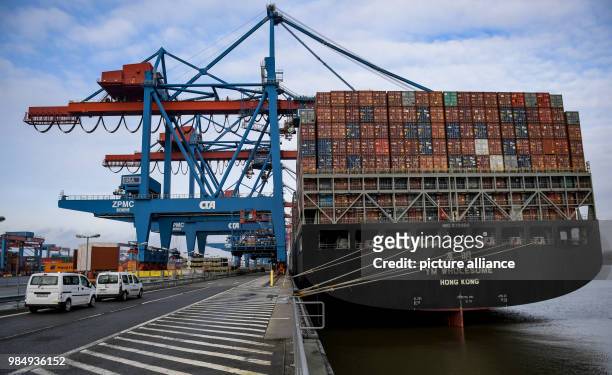 The container freight "YM Wholesome" of the Yang Ming shipping company lying at anchor by the container bridge cranes of the Hamburg Hafen und...
