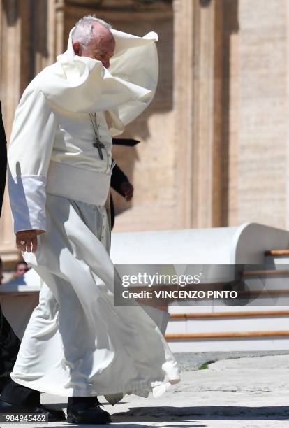 Pope Francis walks as his mantle is lifted by gusts of wind, in St. Peters square at the Vatican at the end of his weekly general audience on June...