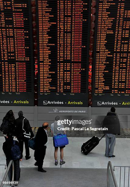 Passengers look at flight information board which indicates cancelled flights in a terminal at the Charles-de-Gaulle airport in Roissy on April 16,...