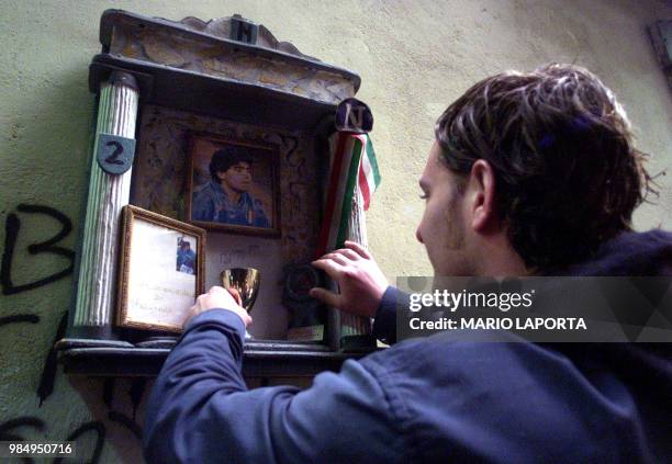 Fan adjusts a votice chapel to support famous Argentinian soccer star Diego Maradona, in a street of downtown Naples, 22 April 2004. Maradona was...