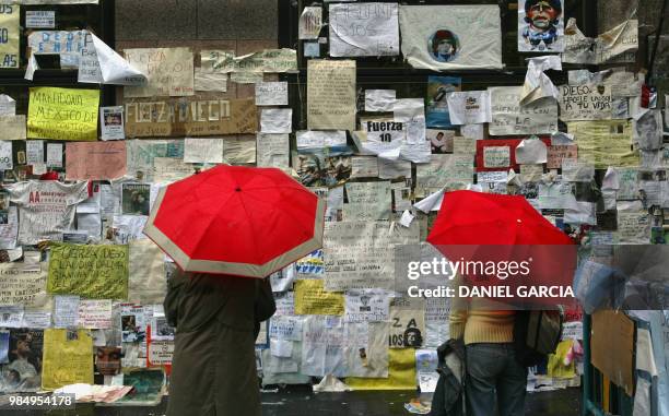 Women read messages stuck on the front wall of the clinic where former football star Diego Maradona is hospitalized in Buenos Aires, 29 April 2004....