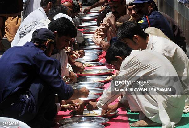 Impoverished Pakistanis eat charity food on a street in Karachi on April 16, 2010. Seventeen million Asians have fallen into extreme poverty due to...