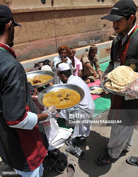 Pakistani volunteers distribute charity food to the needy on a street in Karachi on April 16, 2010. Seventeen million Asians have fallen into extreme...