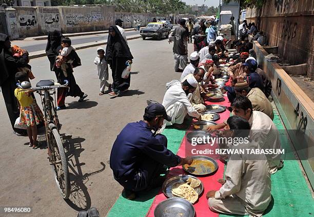 Impoverished Pakistanis eat charity food on a street in Karachi on April 16, 2010. Seventeen million Asians have fallen into extreme poverty due to...