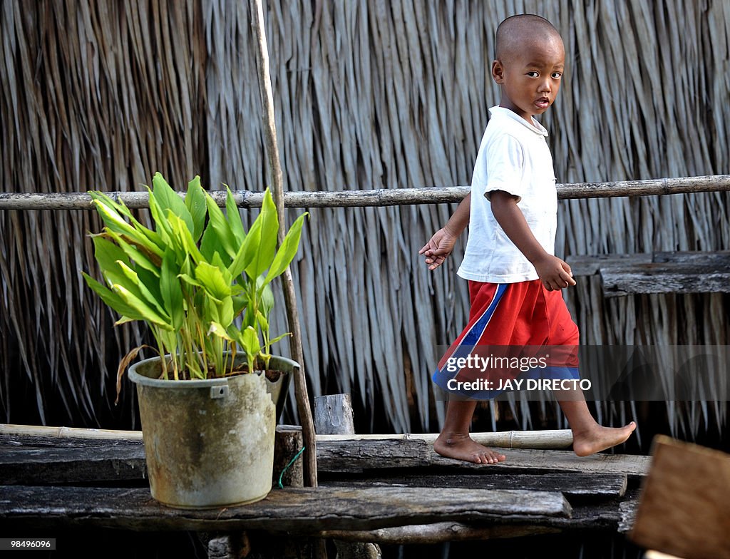 A child walks in front of stilt houses a