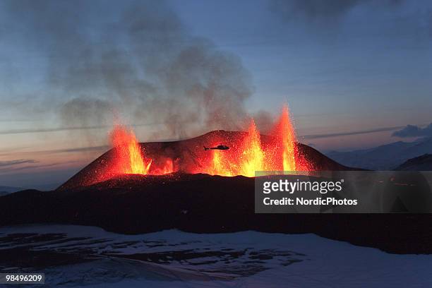 Helicopter flies in front of lava shooting from a volcanic eruption between the Myrdalsjokull and Eyjafjallajokull glaciers on March 24, 2010 in...