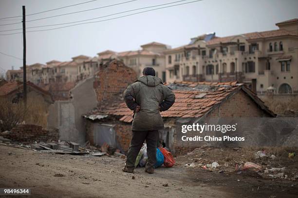 Resident stands at a shanty town near villas under construction on April 15, 2010 in Changchun, Jilin Province, China. Many low-income residents...