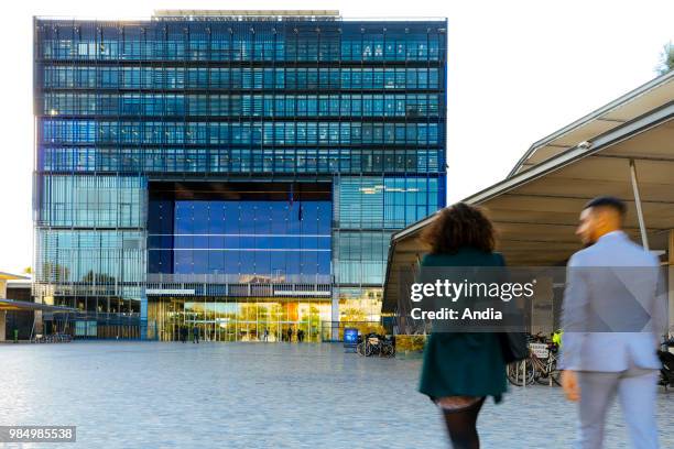 Montpellier : the city hall designed by architects Jean Nouvel and Francois Fontes. Two persons viewed from behind walking on the square.