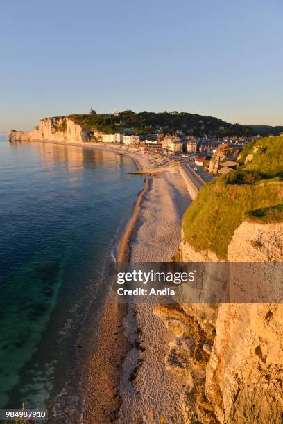 Etretat , town along the 'Cote d'Albatre' , in the area called 'pays de Caux'. Pebble beach wit the city and the cliffs at nightfall.