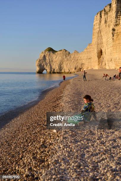 Etretat , town along the 'Cote d'Albatre' , in the area called 'pays de Caux'. Pebble beach with the arch 'Porte d'Amont' at nightfall.