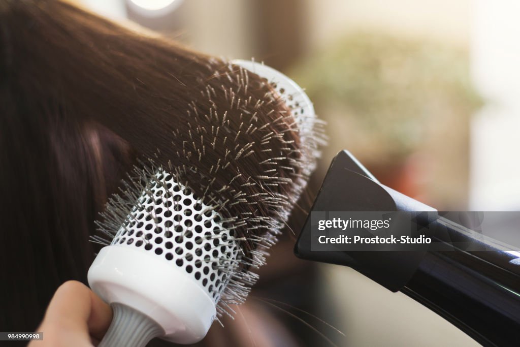 Hairdresser drying woman's hair in beauty salon