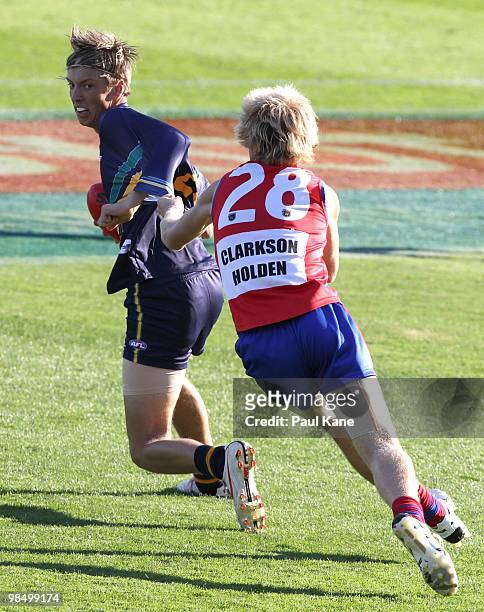 Michael Bussey of the AIS attempts to break a tackle by Laine Rasmussen of West Perth during the trial match between the AIS AFL Academy and West...