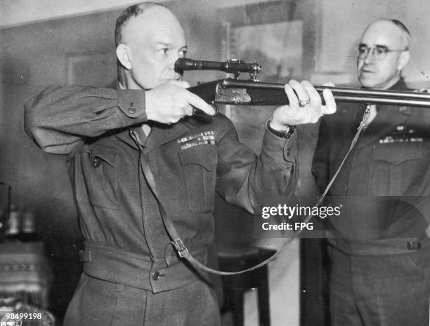 Commanding General of U.S. Army Europe, Dwight D. Eisenhower firing a German-made combination rifle-shotgun with telescopic sight, during a tour of...