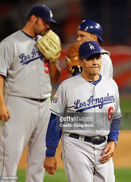 Manager Joe Torre walks off the mound as relief pitcher Jonathan Broxton of the Los Angeles Dodgers talks with catcher Russell Martin while taking on...