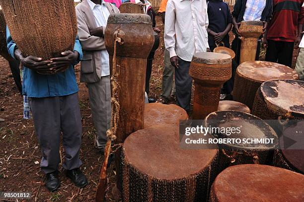 Man specially chosen for the occasion holds a ceremonial drum on his arms as others look ahead of a ceremony were the instruments are later presented...