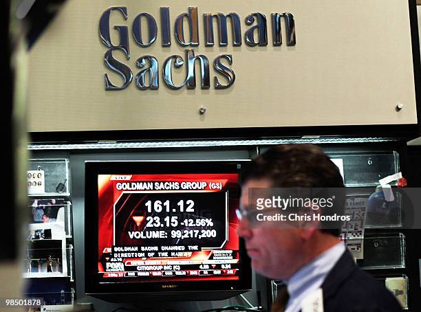 Financial professional works in the Goldman Sachs booth on the floor of the New York Stock Exchange while a television reports airs about the...