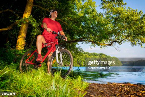 urlaub in polen - erwachsener mann reitet ein fahrrad entlang des sees in masuren-land - masuria stock-fotos und bilder