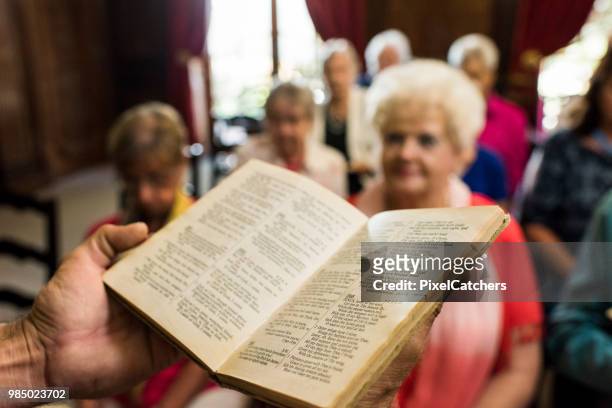 priest holding a book of psalms addressing the congregation - preacher stock pictures, royalty-free photos & images