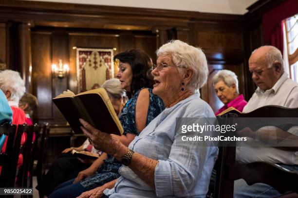 side view of a senior women singing in church - church stock pictures, royalty-free photos & images