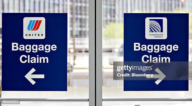 Signs point to baggage claim areas for Continental Airlines, right, and United Airlines at O'Hare International Airport in Chicago, Illinois, U.S.,...
