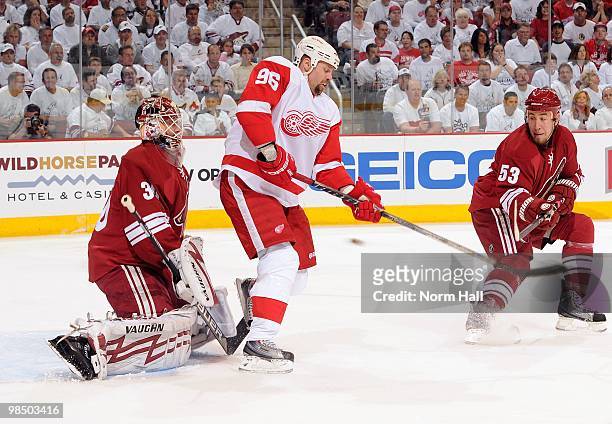 Tomas Holmstrom of the Detroit Red Wings and Derek Morris of the Phoenix Coyotes try to redirect a shot while standing in front of Coyotes Goaltender...
