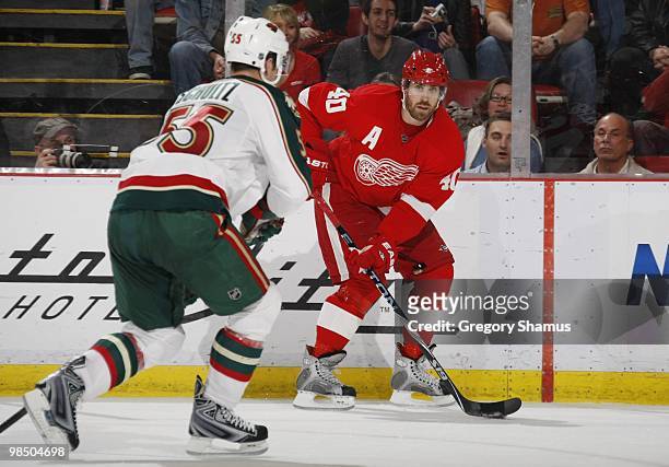 Henrik Zetterberg of the Detroit Red Wings looks to play the puck against Nick Schultz of the Minnesota Wild during their NHL game on March 11, 2010...